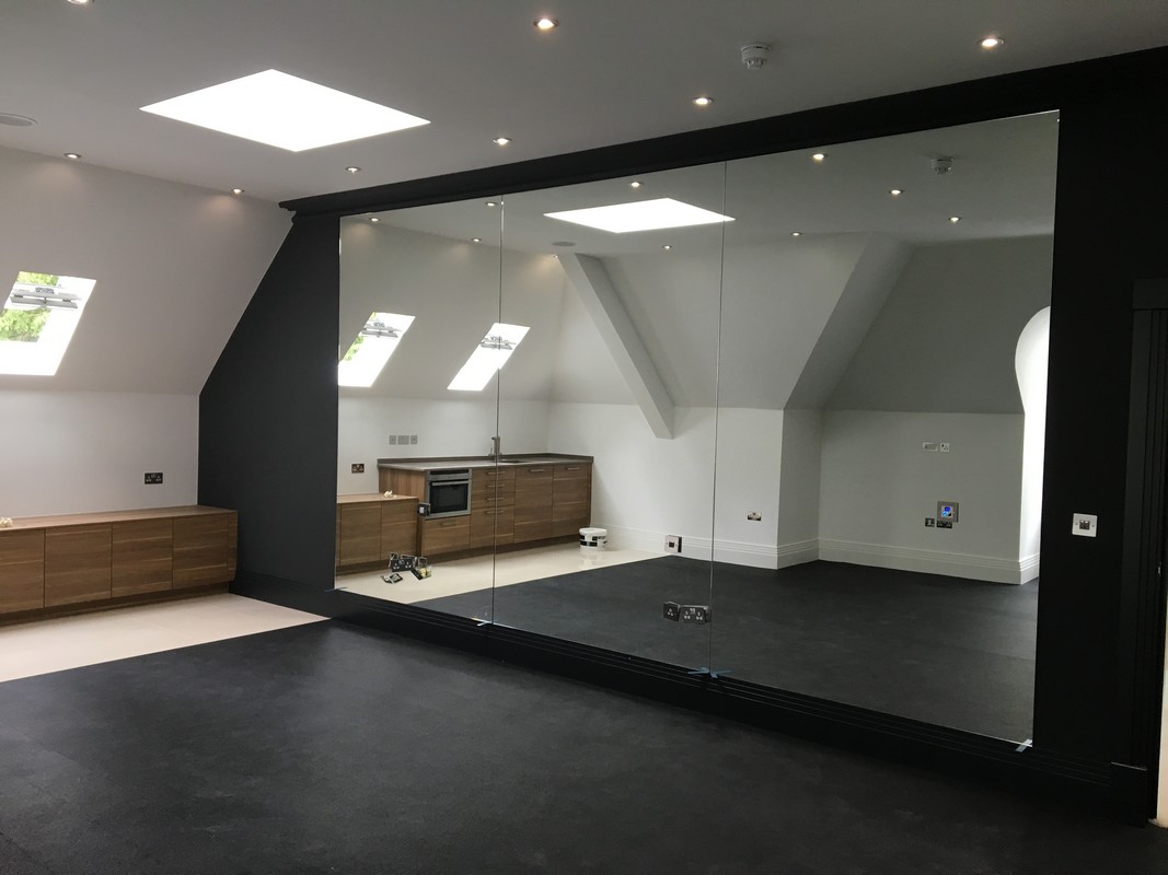 Frameless glass wall dividing loft conversion in Ruislip